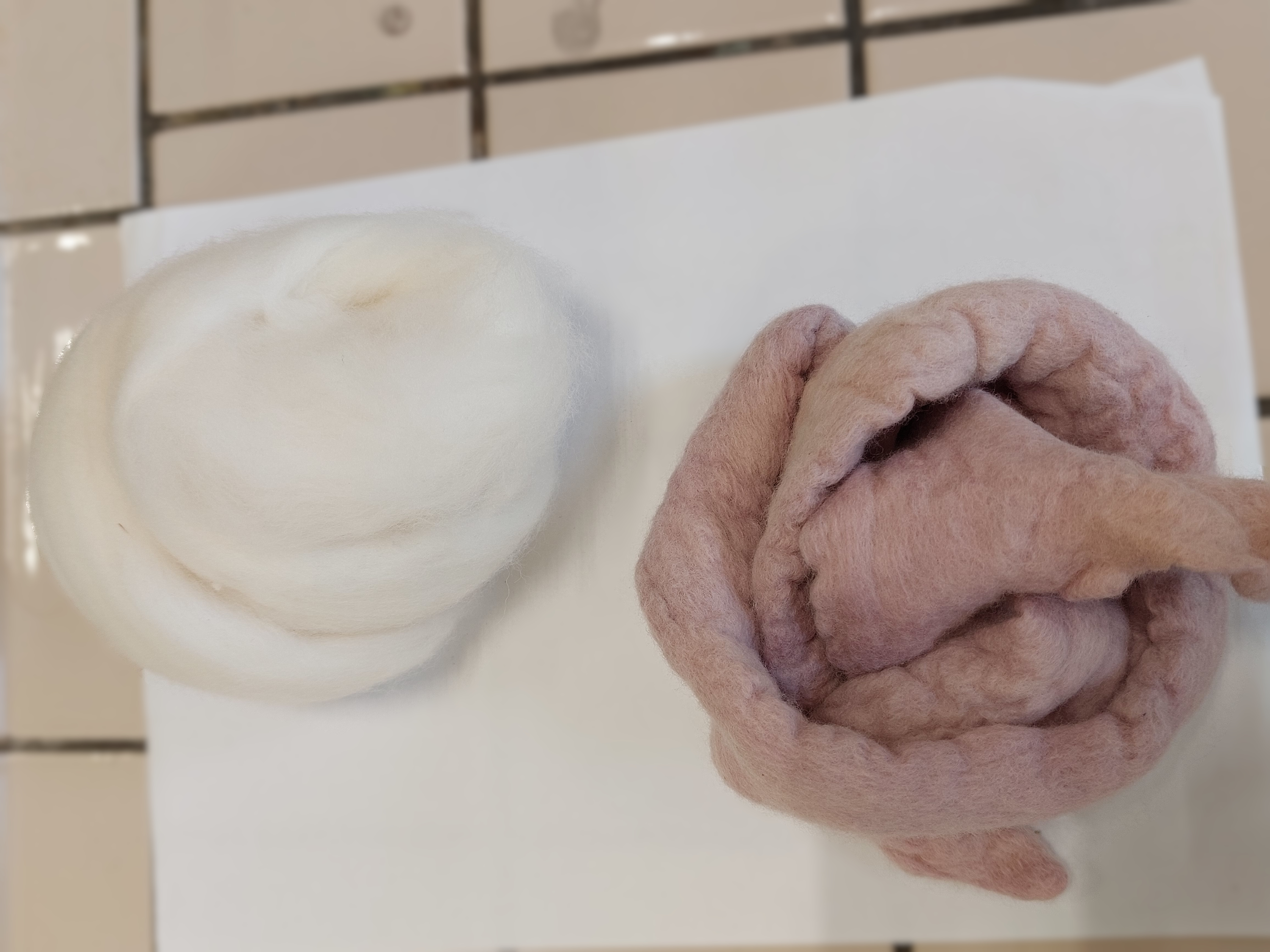 a batch of white, uncoloured wool next to a batch of light purple coloured wool