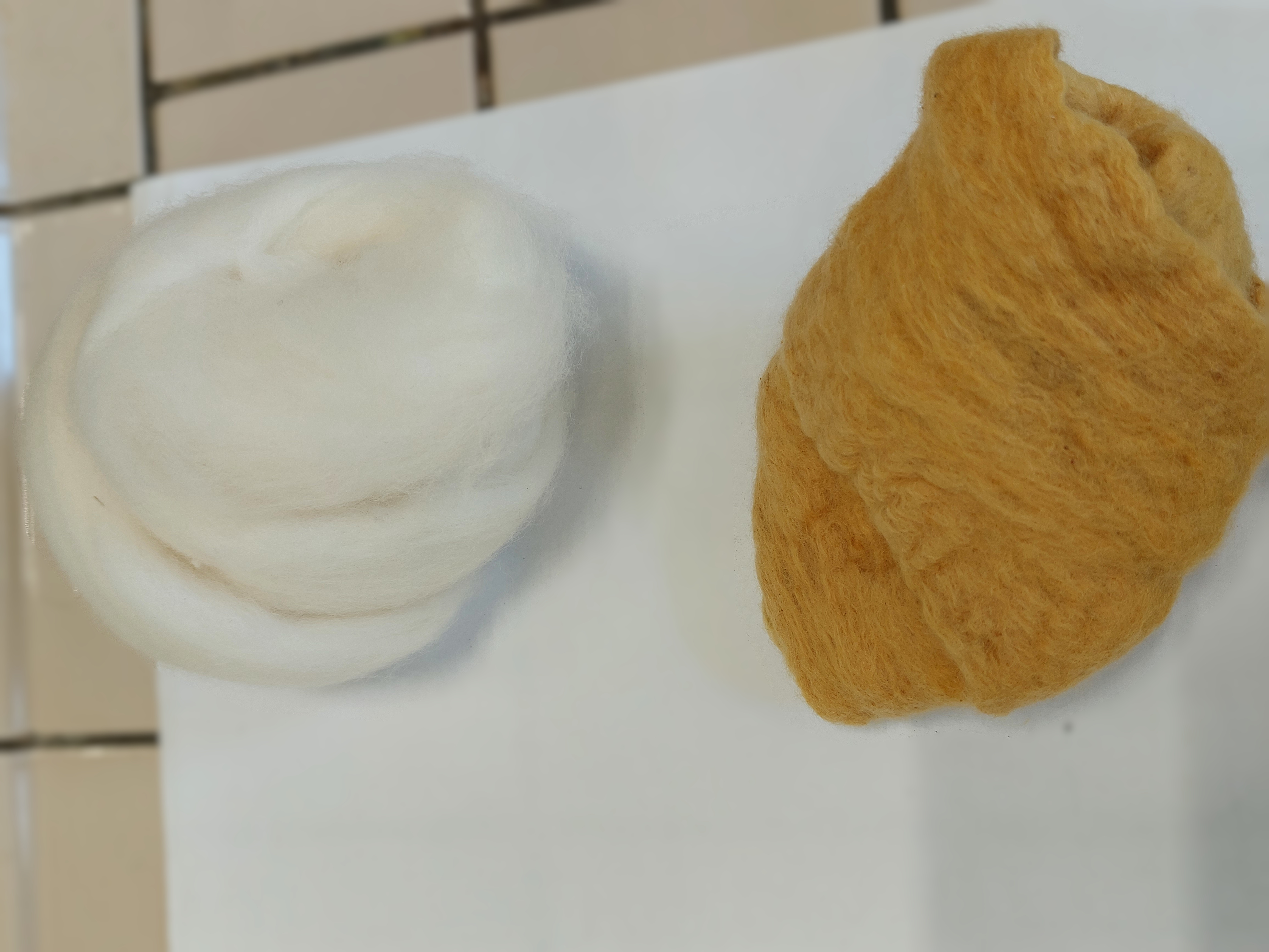 a batch of white, uncoloured wool next to a batch of brownish yellow coloured wool